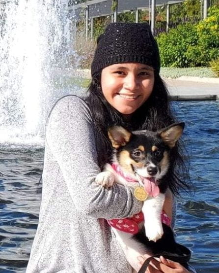 Headshot of Esther Jimenez in front of a fountain with her corgi